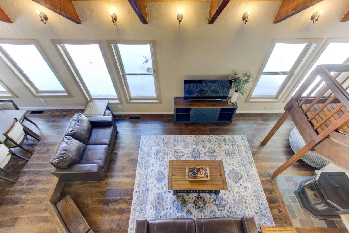 This angle showcases a bright, comfortable seating area arranged around a central coffee table styled with decorative items. Large windows bathe the room in natural light and offer direct views of the snowy forest outside, while the furniture layout invites group gatherings and relaxed leisure.