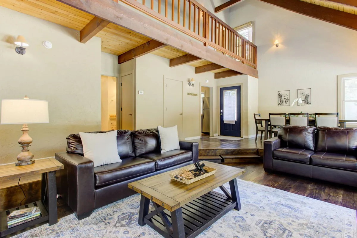 A welcoming interior space with leather sofas, a wooden coffee table, and an open loft area. This scene hints at the transition from the practical entry and mudroom into the relaxing living areas, capturing the flow from adventure to comfort.